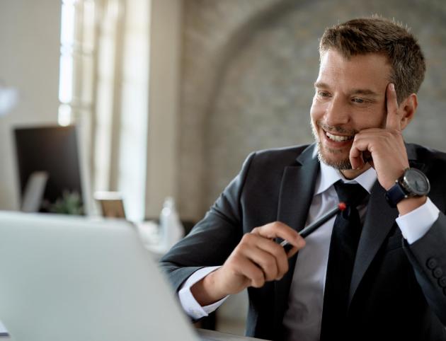 Happy mid adult businessman working on a computer and reading an e-mail in the office.